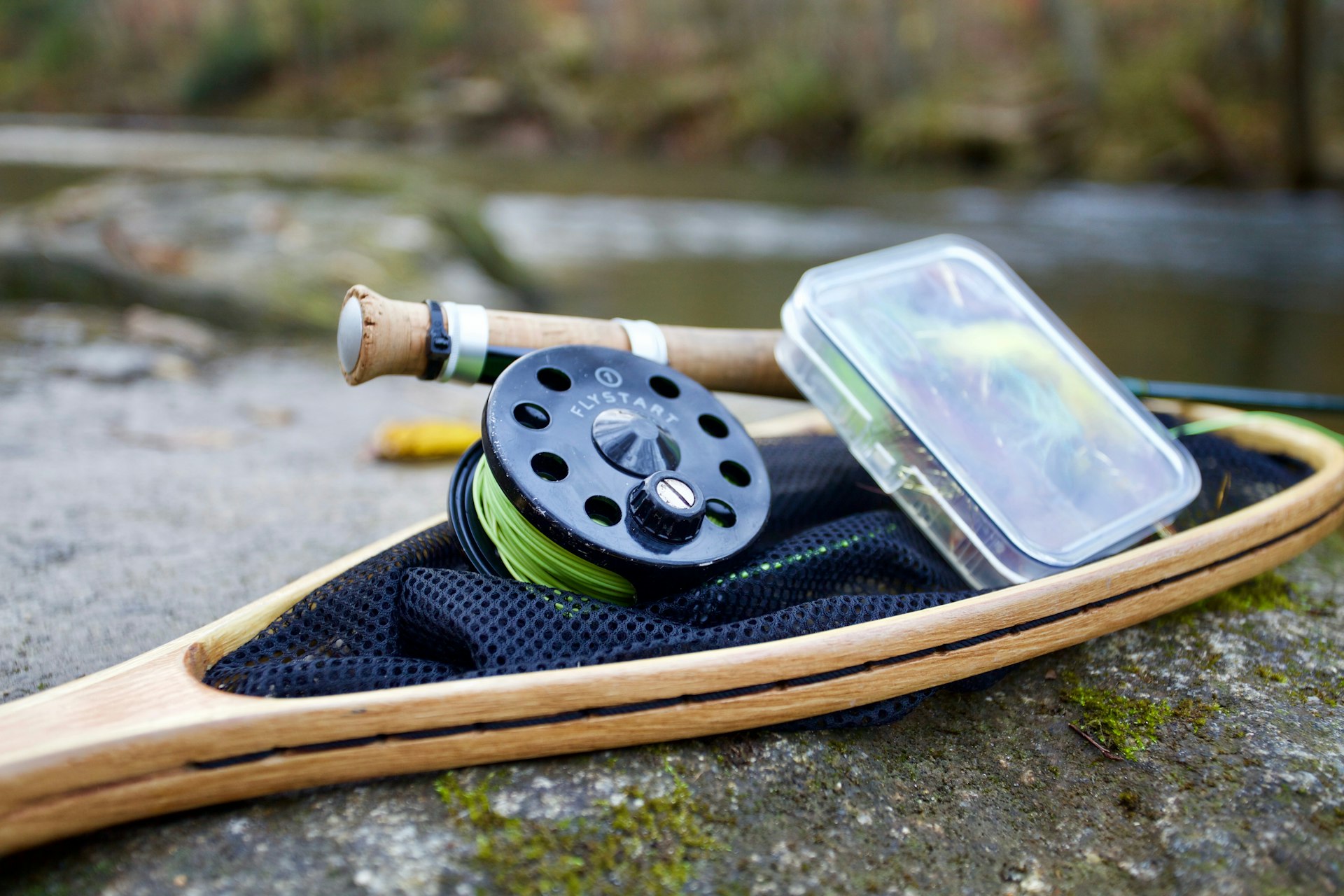 fly reel and fly box on a landing net